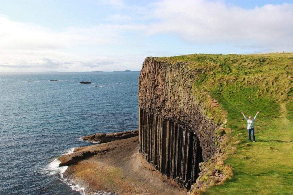 Dramatic cliffs on the Isle of Skye in Scotland with a traveler standing the distance