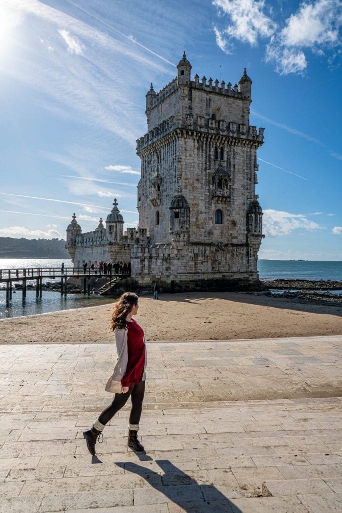 kate storm in a red dress in front of the belem tower in sunny lisbon vs porto