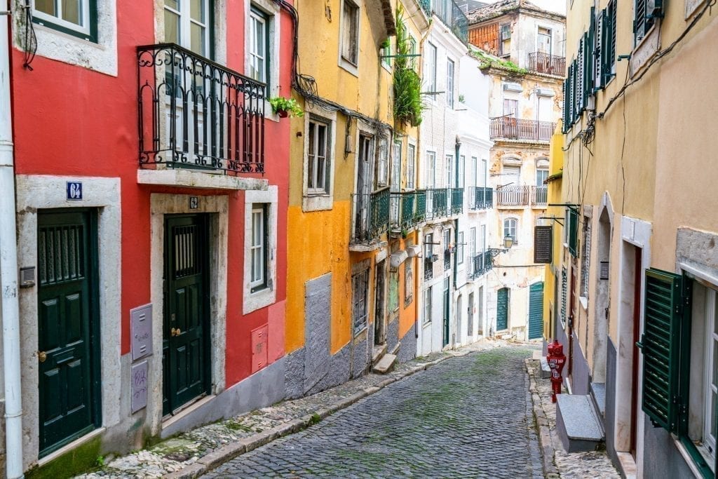 Colorful street in Lisbon Portugal with red and yellow buildings on the left