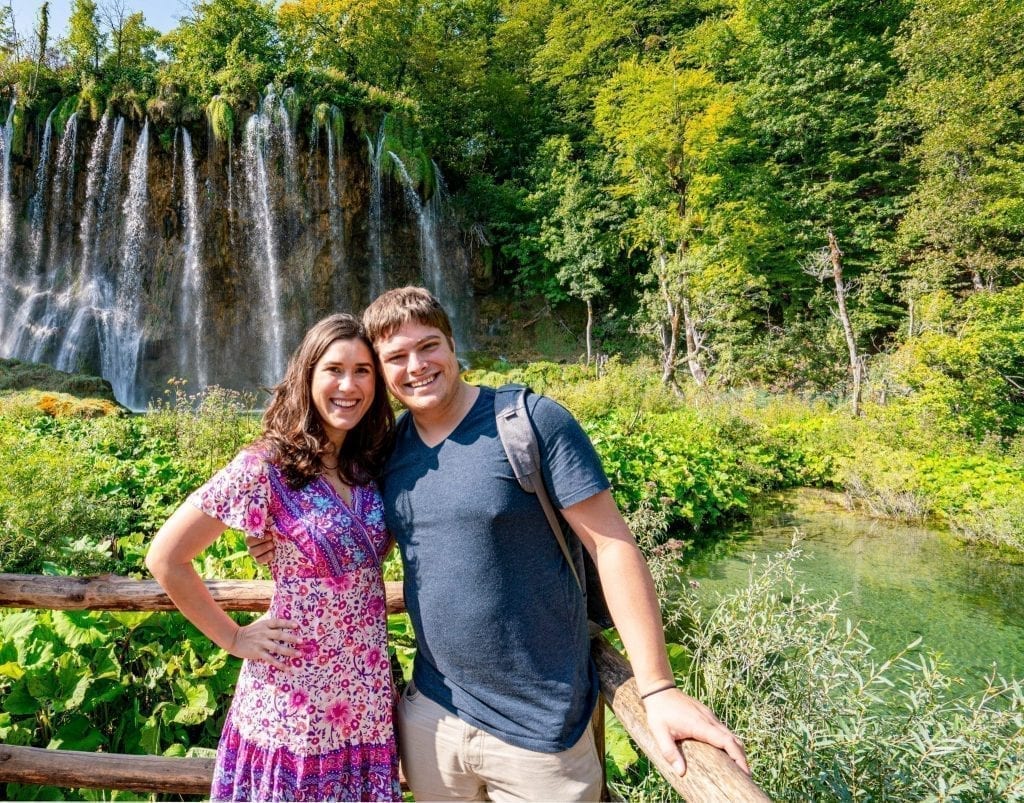  Kate Storm y Jeremy Storm de pie frente a una cascada al visitar el Parque Nacional de los Lagos de Plitvice, Croacia