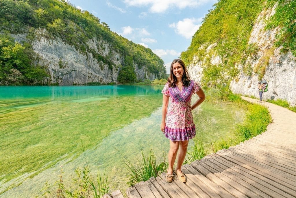 Kate Storm in a pink dress standing on a boardwalk over a lake on a Plitvice Lakes holiday