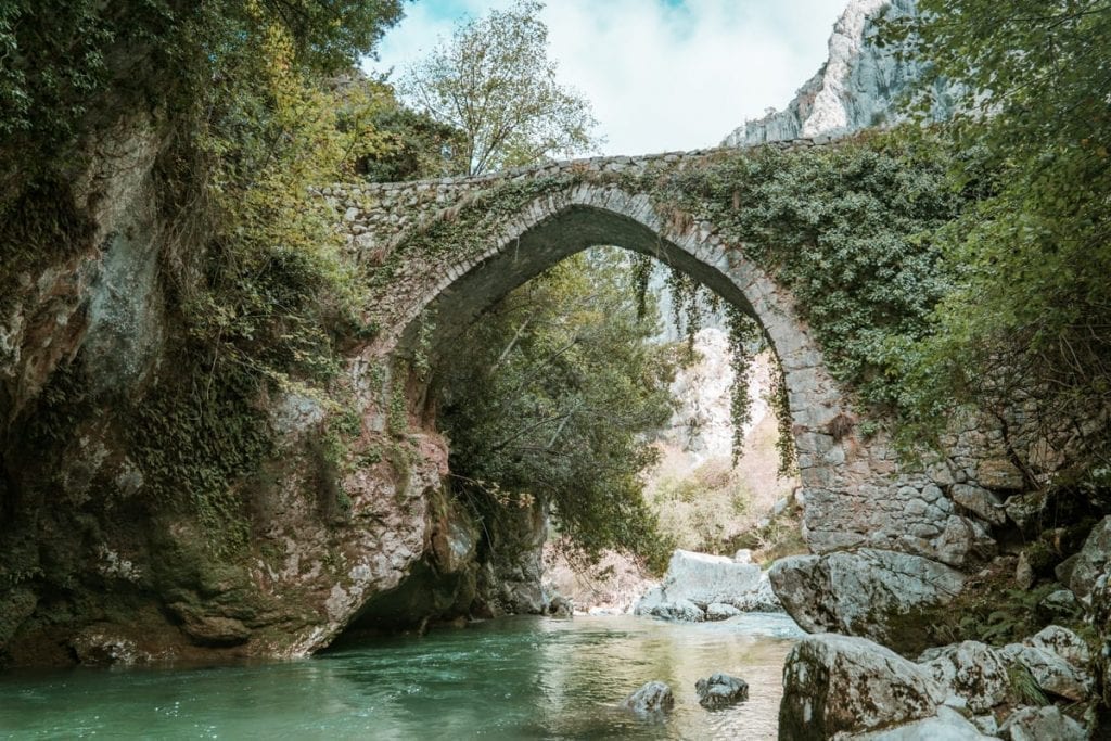 Spain Picos de Europa Puente la Jaya stone bridge over a bright blue river