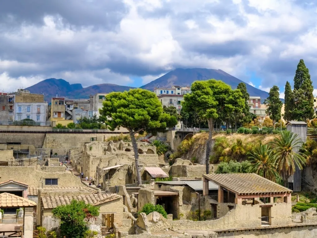 View of ruins of Herculaneum from above with Mount Vesuvius in the background. Herculaneum is one of the easiest Sorrento day trips to take independently.