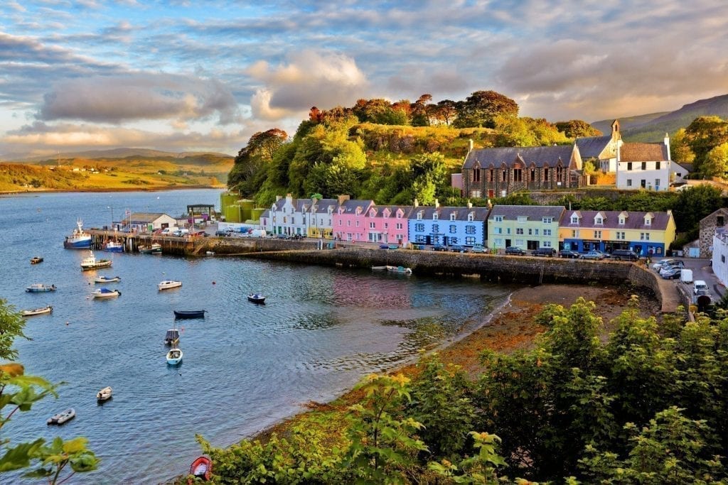 Colorful village set along the water on the Isle of Skye in Scotland with boats parked in the harbor--Scotland is home to some of the best Europe itinerary road trip options around!