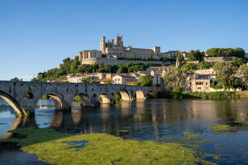 historic bridge and river in narbonne france with gothic cathedral in the background, an interesting stop on europe road trips