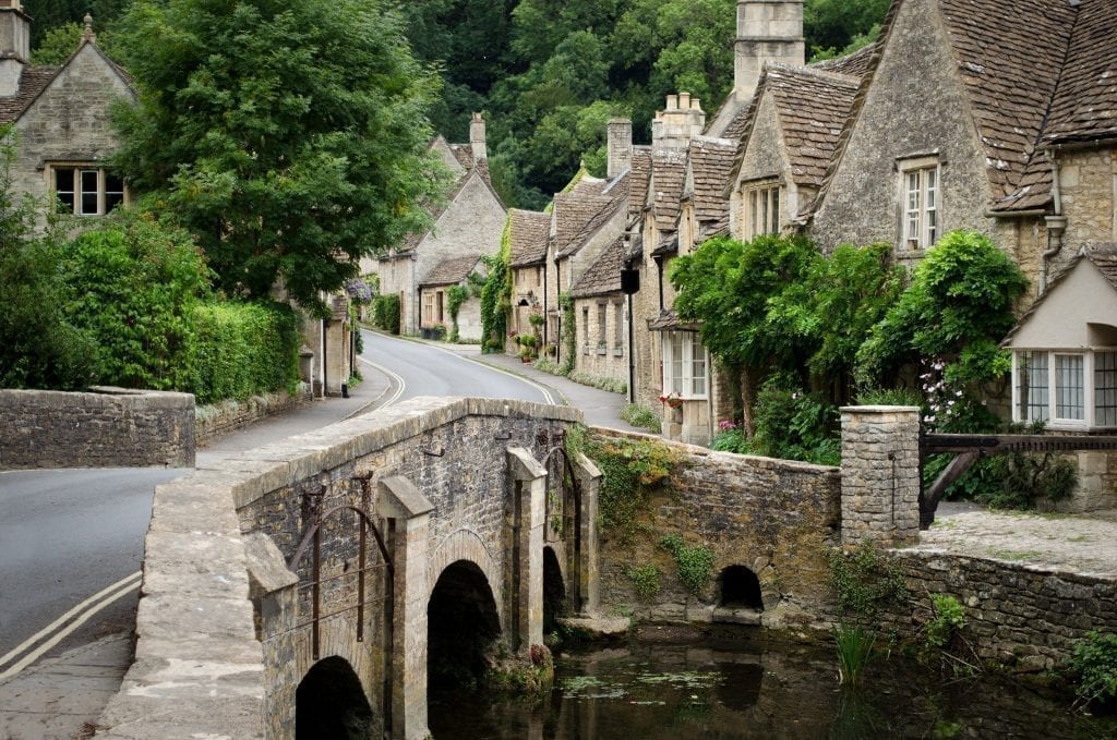 Castle Combe village in the Cotswolds with a small stone bridge in the foreground and stone houses in the background