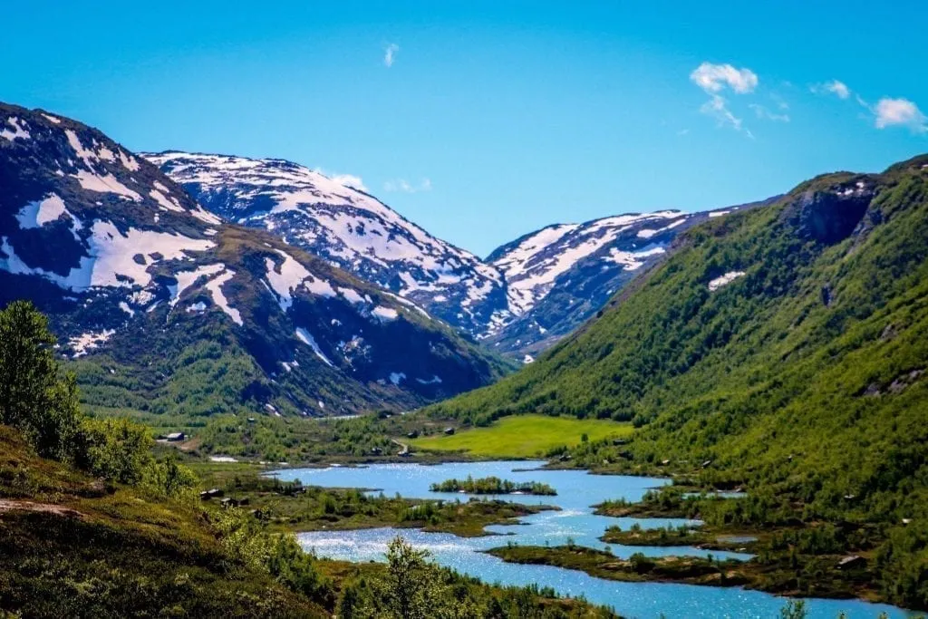 Bright blue fjord in Norway as seen with snowcapped mountains in the background
