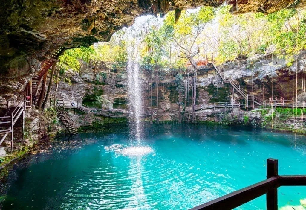 Cenote X'canche as seen from the interior of the small cave. Also known as the ek balam cenote. A waterfall is in the left side of the photo and the water is turquoise