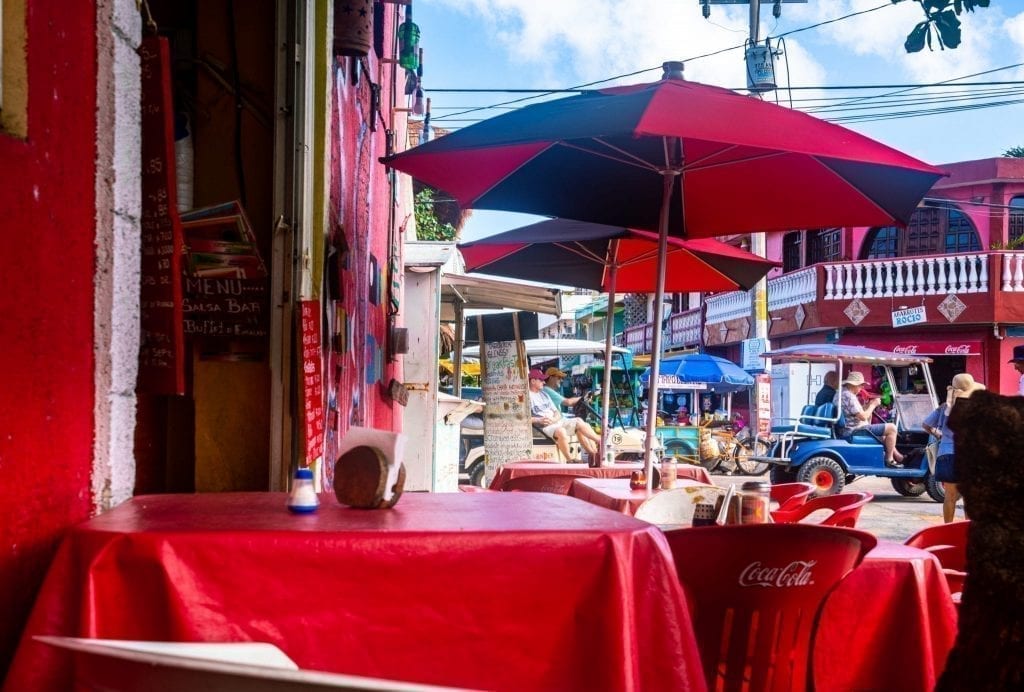 Outdoor restaurant in Mexico with red tablecloths and red umbrellas shading the tables