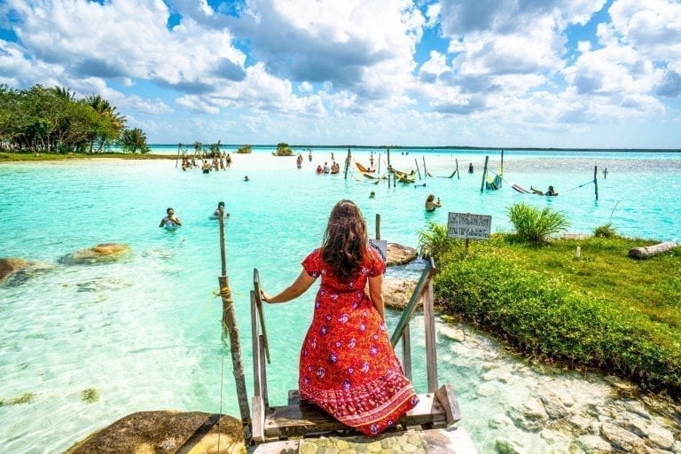 kate storm in a red dress in bacalar mexico, how to save money to travel the world helped us reach this destination