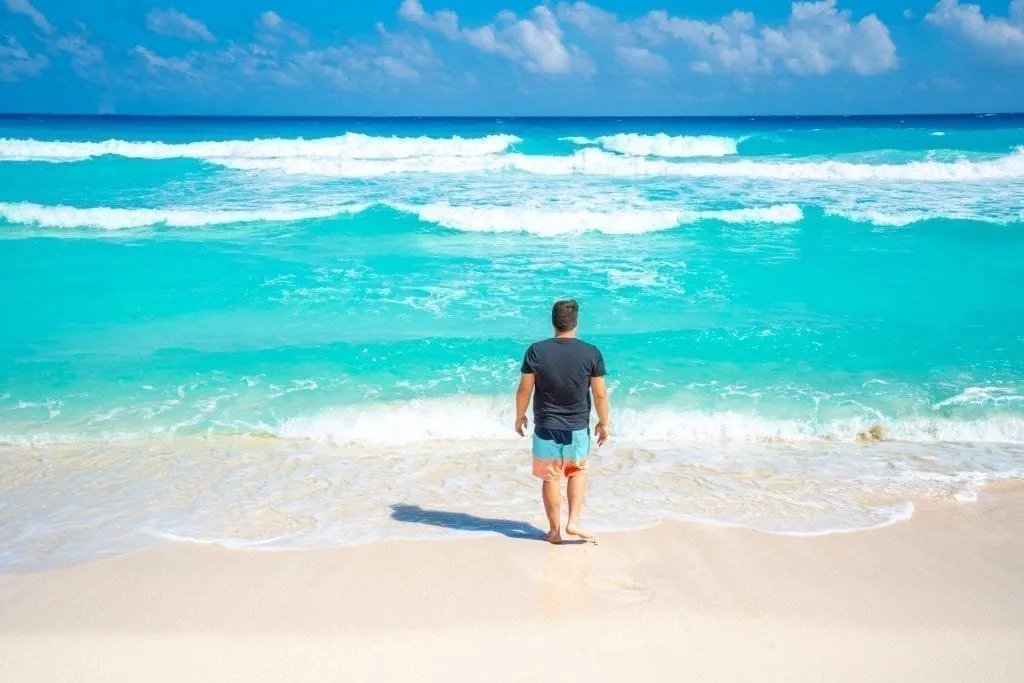 Jeremy Storm walking into a turquoise sea in Cancun Mexico