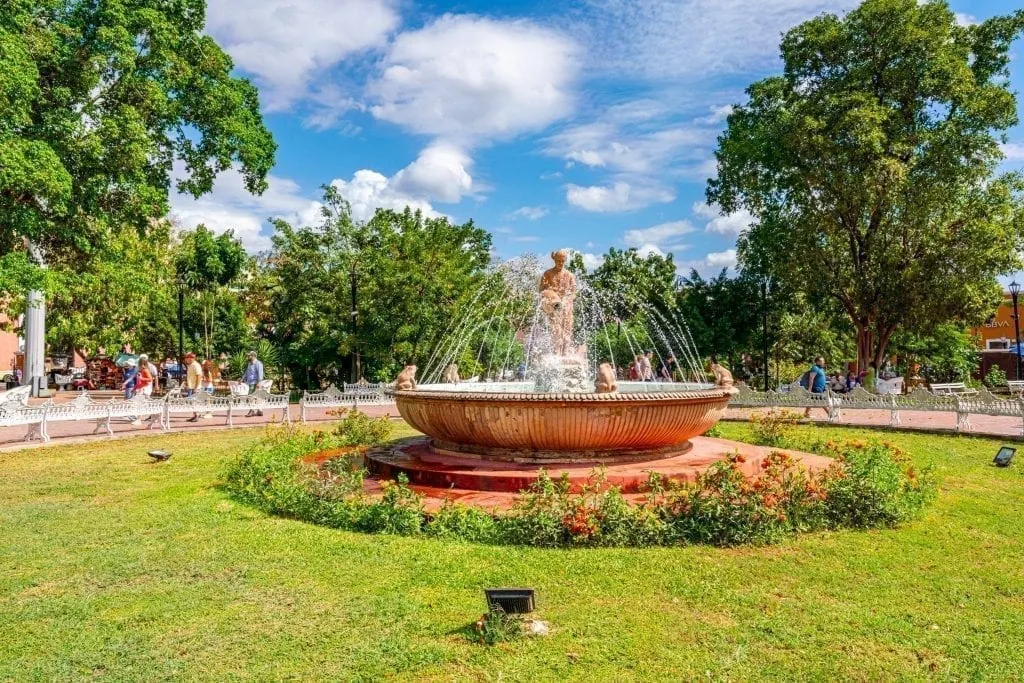 fountain in the center of the zocalo surrounded by a green lawn