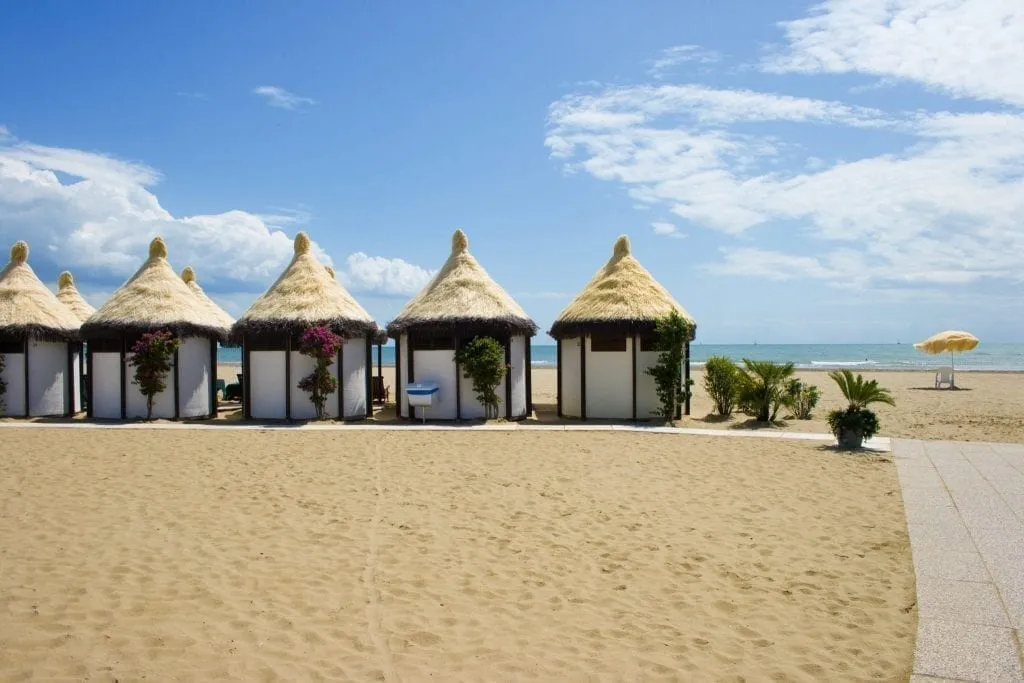 Sandy Lido Beach in Venice, with shady huts visible on the left and the water visible in the distance