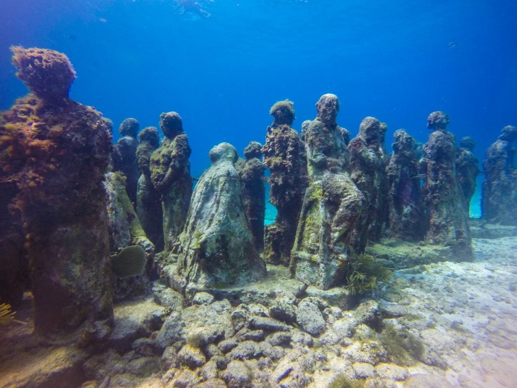 underwater photo of statues of humans at musa museum cancun mexico