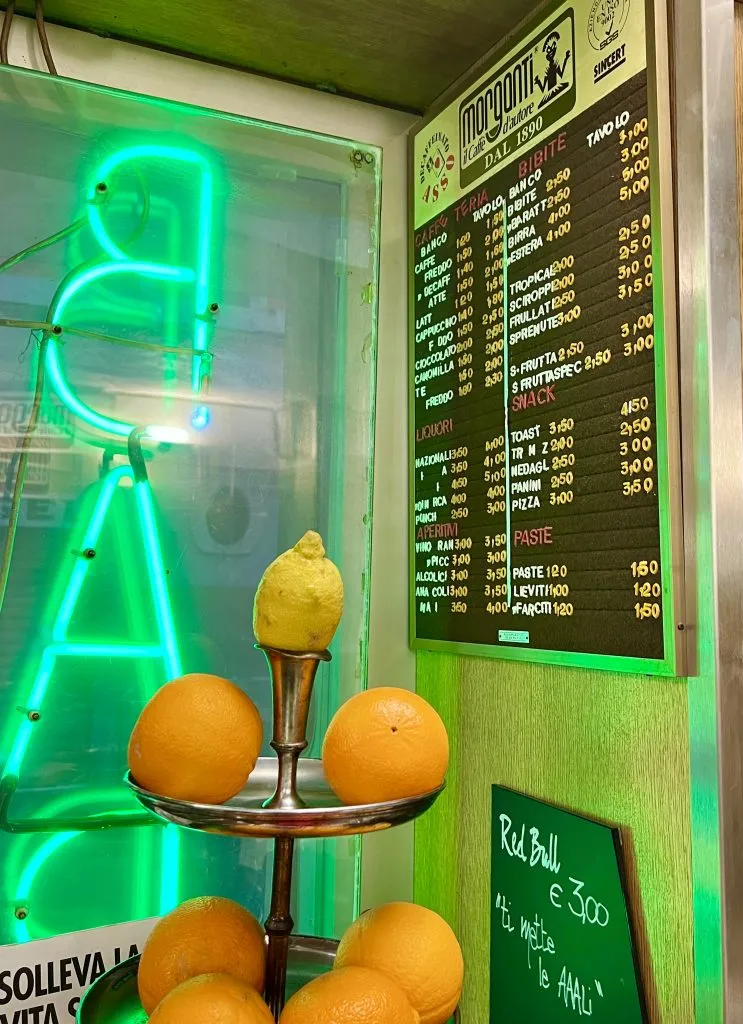 menu hanging inside an italy coffee bar with a neon green "bar" sign to the left