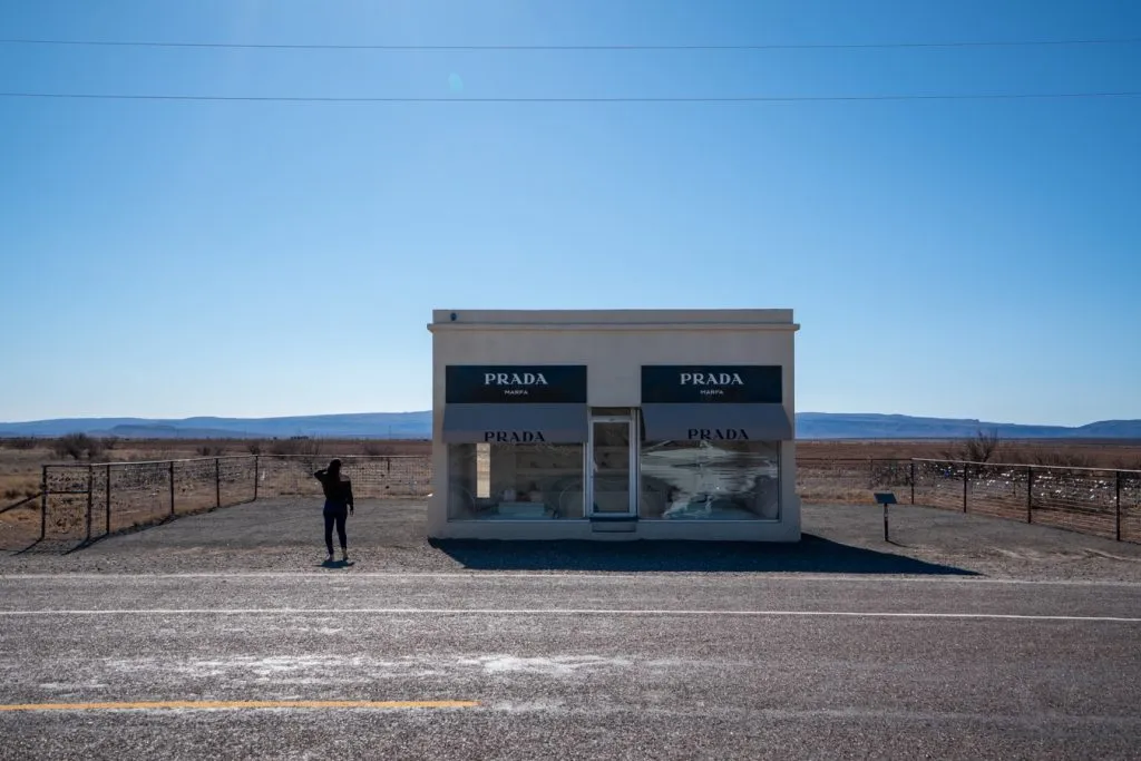 kate storm in front of prada marfa in west texas, one of the best road trips in america