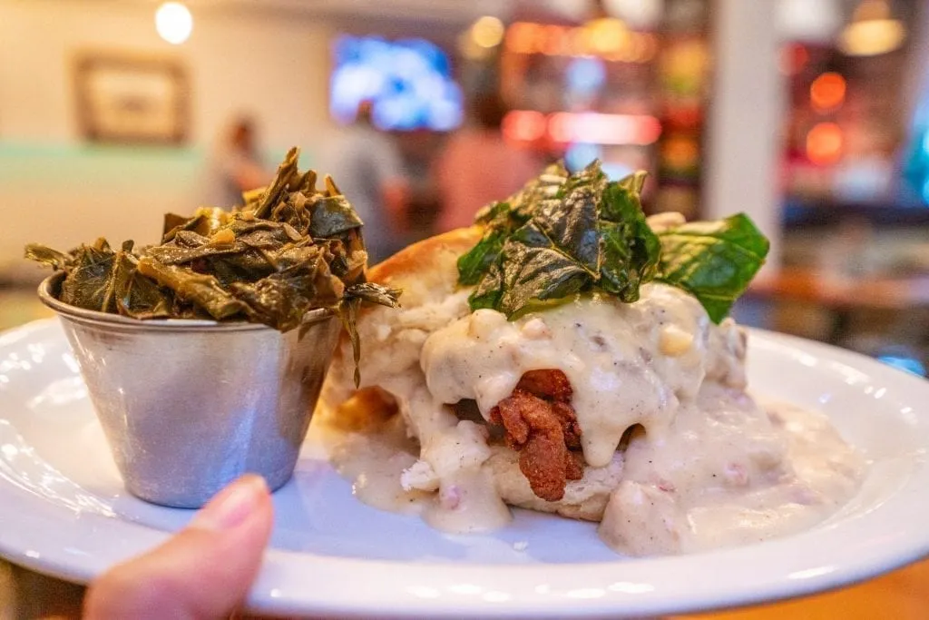 Chicken biscuit and collards being held up to the camera in Savannah GA