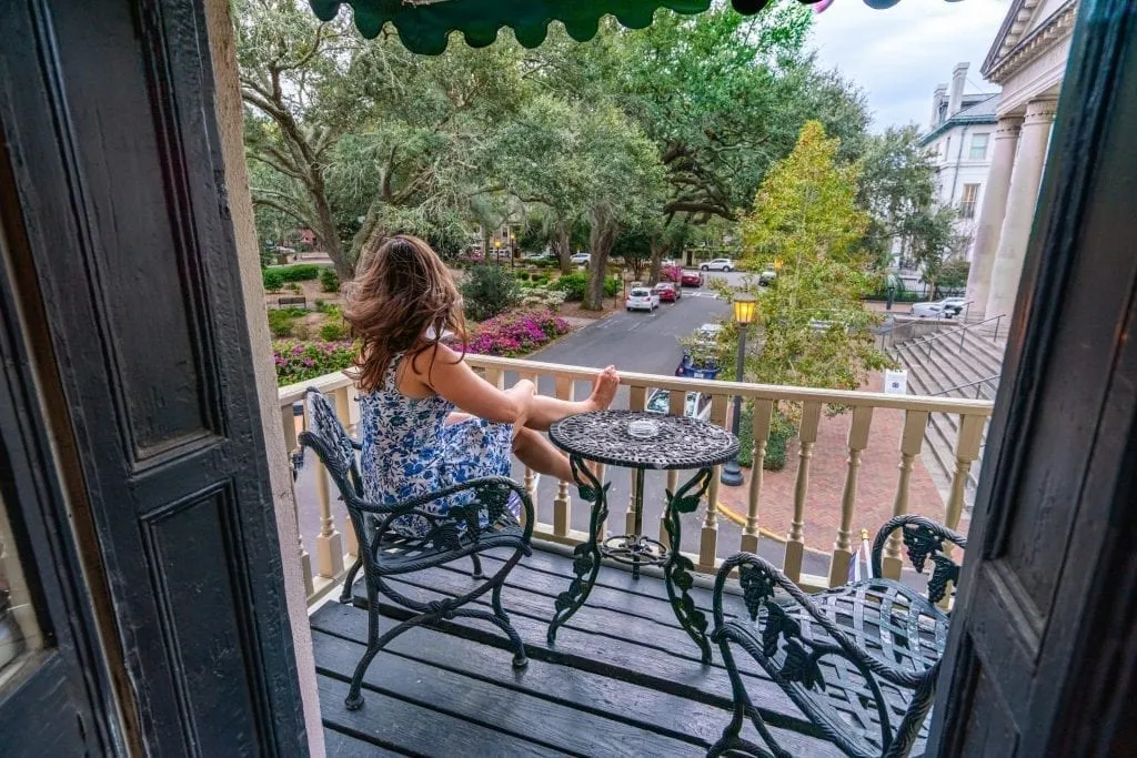 Kate Storm in a blue dress overlooking Chippewa Square from the balcony of Foley House Inn, one of the most instagrammable places in Savannah GA