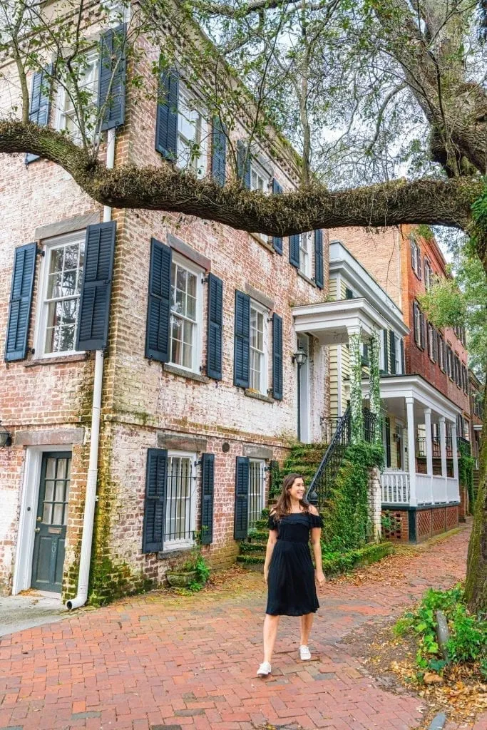 Kate Storm in a black dress in front of a brick home on Jones Street during a long weekend in Savannah GA