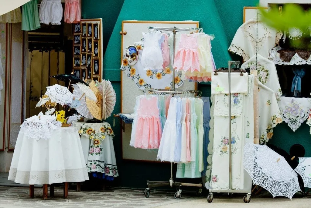 Lace goods for sale outside a colorful house in Burano Italy, one of the best Italy souvenirs