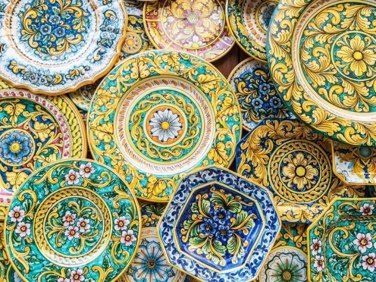 Colorful ceramic plates on display on a wall, one of the best souvenirs from Italy