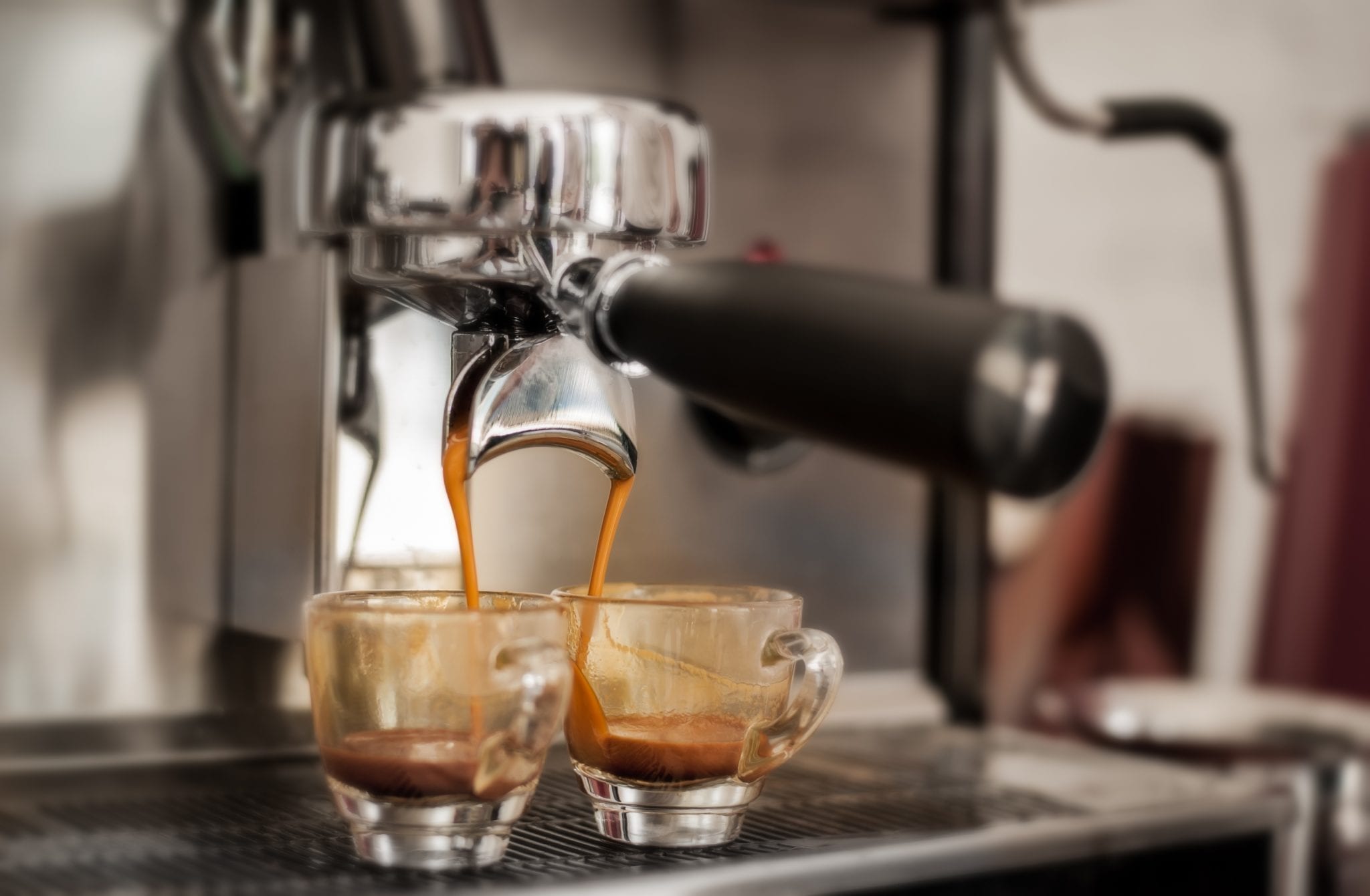 Photo of two espresso shots being filled by a machine, featured photo on our guide to how to order coffee in Italy