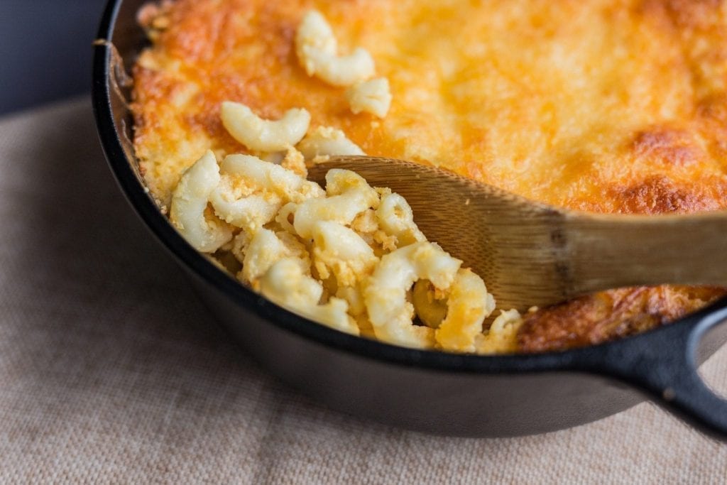 Castiron pan of southern macaroni and cheese with wooden serving spoon stuck in it