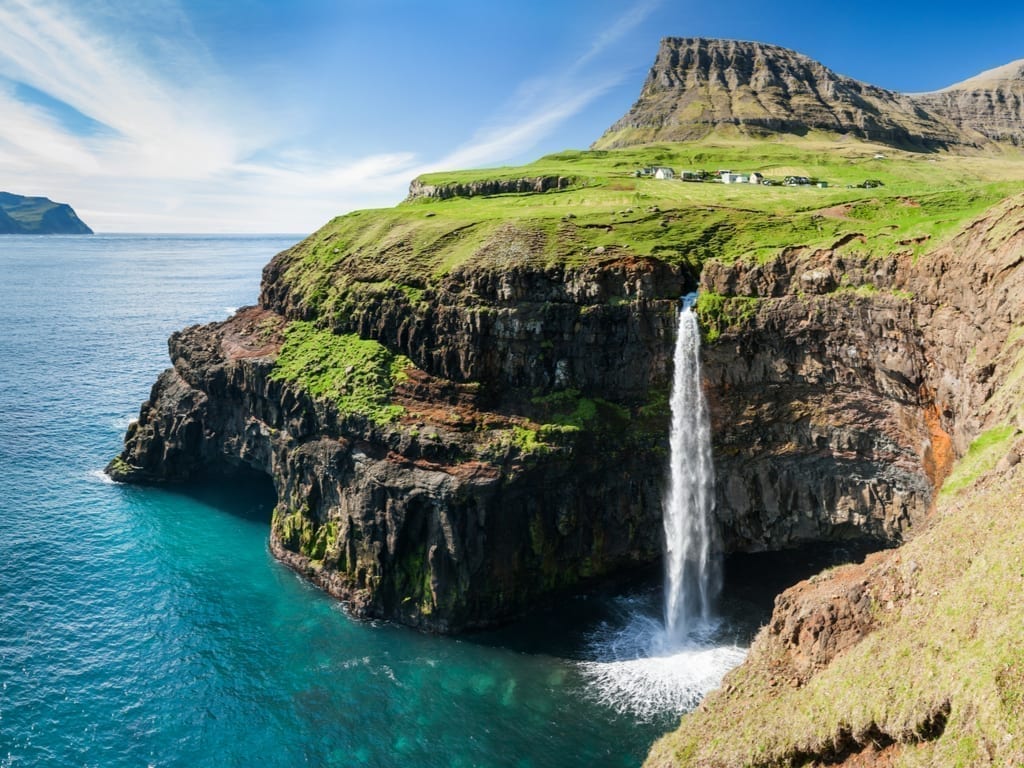 Waterfall into the ocean as seen on the Faroe Islands, one of the best summer places to visit in Europe