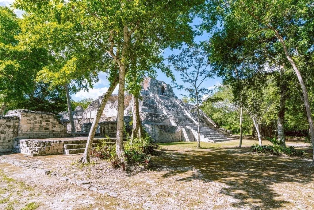 Becan Mayan ruin site in Mexico, an open plaza with a structure visible through the trees
