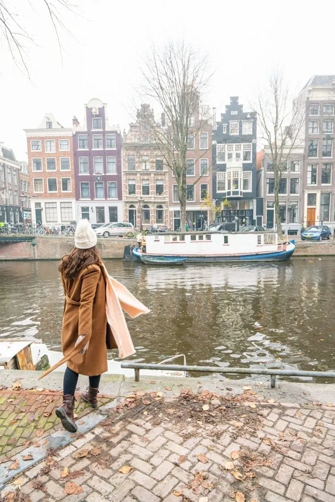 Kate Storm in a brown coat looking over a foggy canal in Amsterdam in December