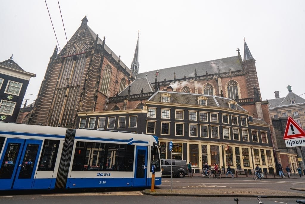 Blue and white tram in Amsterdam passing in front of a large church