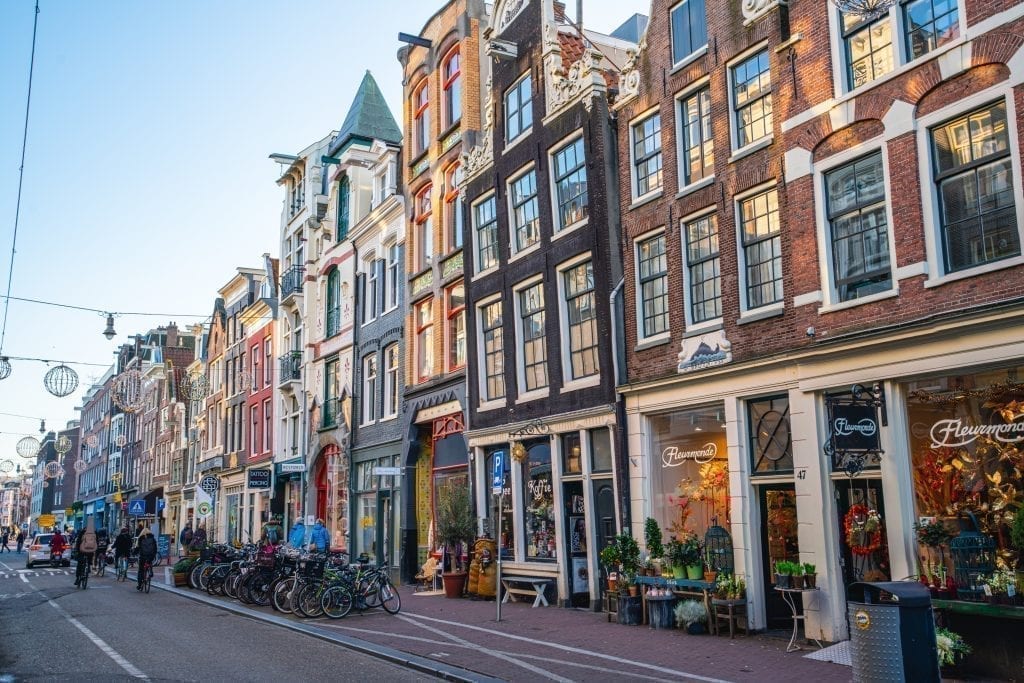 Boutiques lining a street in Amsterdam with typical Dutch houses for the city--views like these are an essential part of seeing Amsterdam in a day