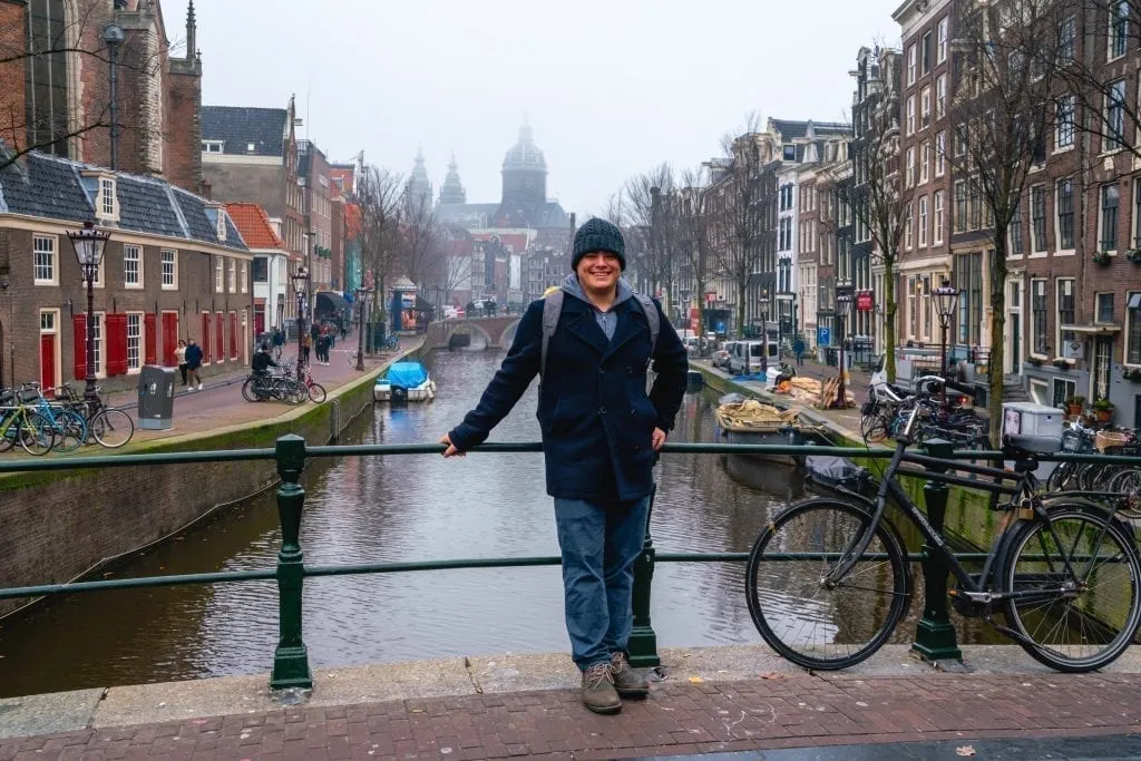 Jeremy Storm leaning against a bridge during one day in Amsterdam on a cloudy evening