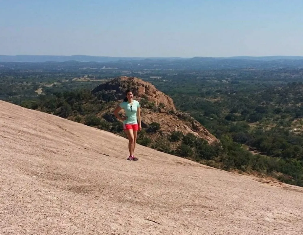 Kate Storm standing on Enchanted Rock near Fredericksburg, one of the best places to visit in Texas