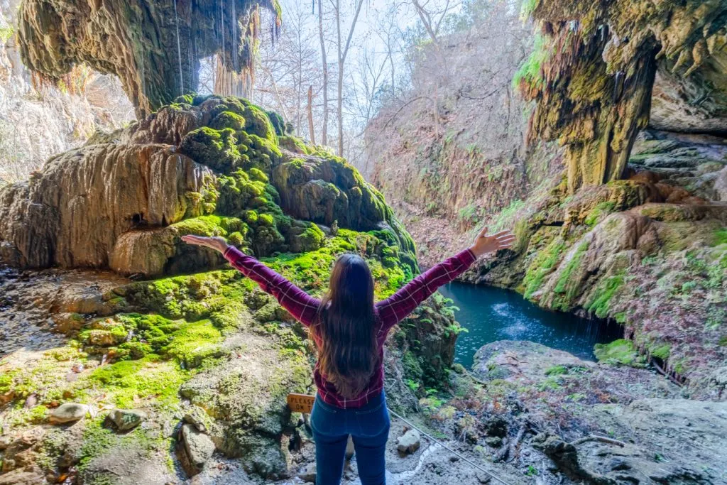 kate storm in front of waterfall at westcave preserve near austin, one of the best weekend getaways in texas