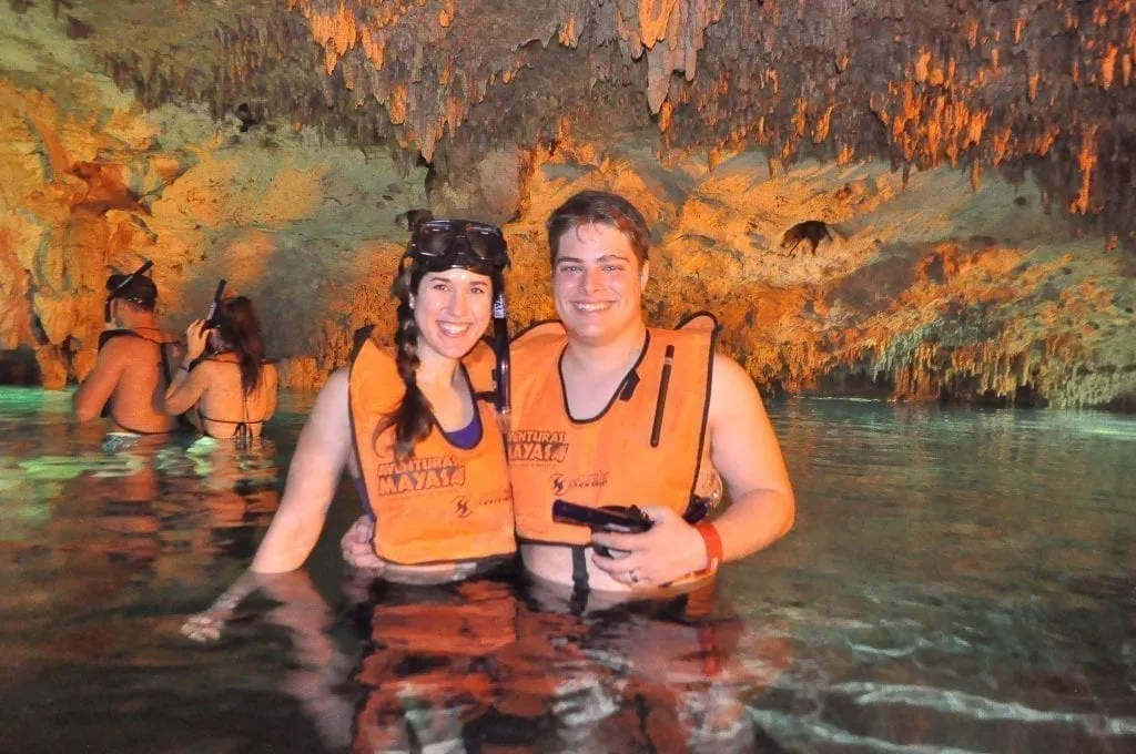 Kate Storm and Jeremy Storm in an enclosed cenote in Riveria Maya Mexico, wearing orange life jackets