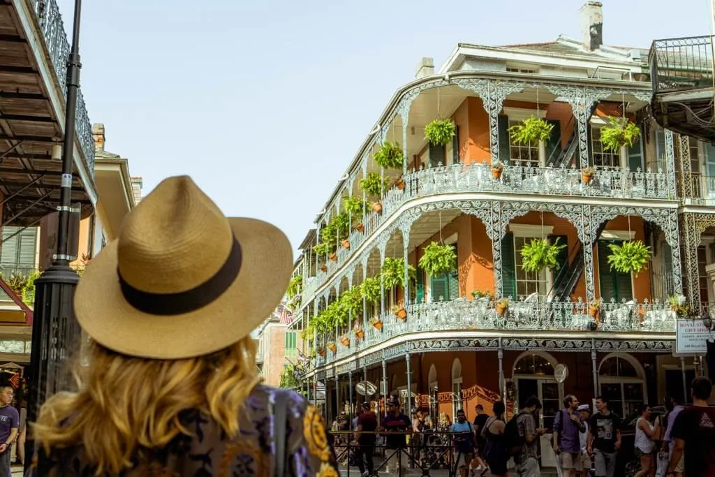 Blonde woman in a straw hat looking at a beautiful brick building in NOLA Garden District, one of the best weekend getaways in the south