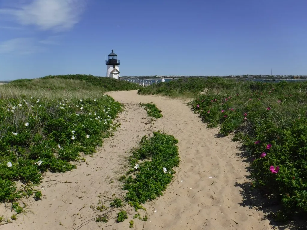 sandy path leading to a lighthouse in nantucket, one of the most romantic us honeymoon ideas