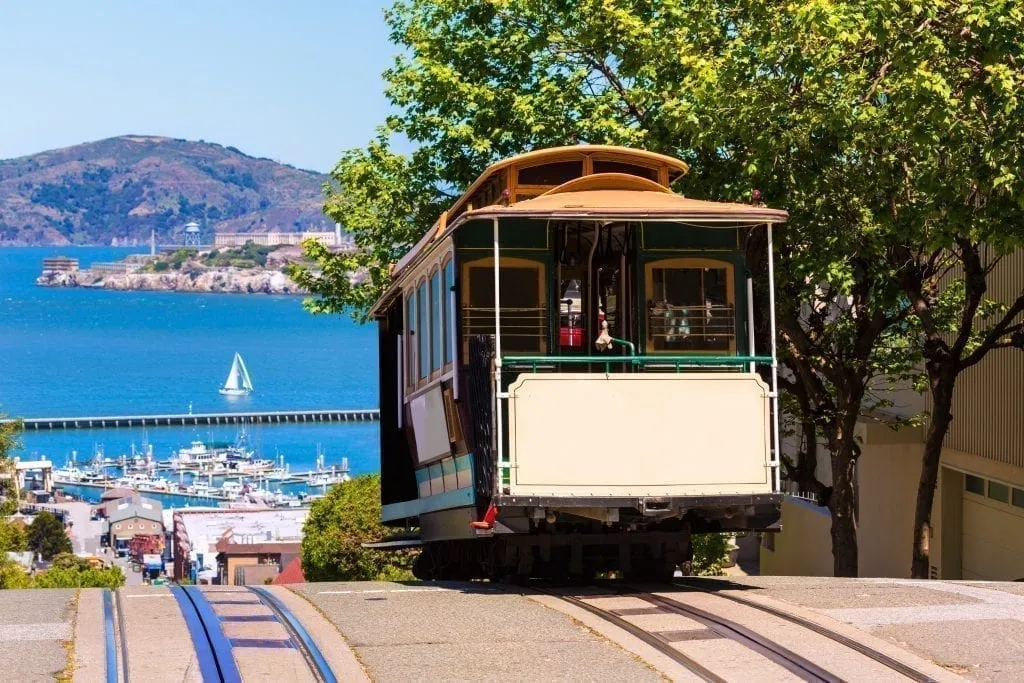 Hyde Street Cable Car in San Francisco CA with ocean visible in the background--riding a cable car is a fun way to get around during a 3 day San Francisco itinerary