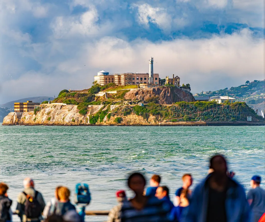 view of alcatraz island from approaching ferry, crowd of people looking toward it in the foreground