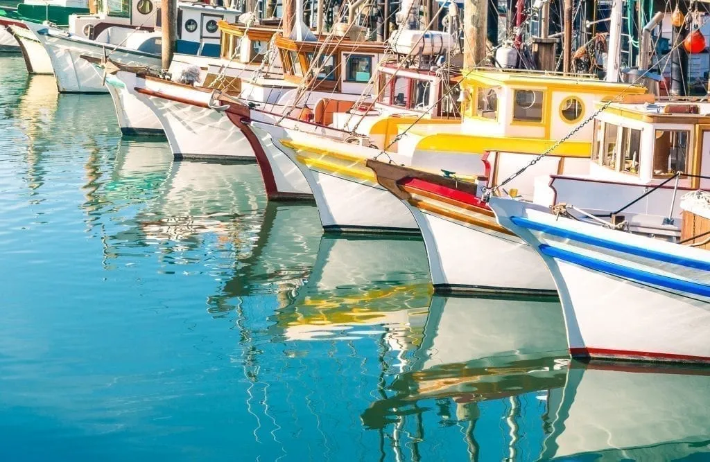 Colorful boats reflecting in the water at Fisherman's Wharf in San Francisco CA