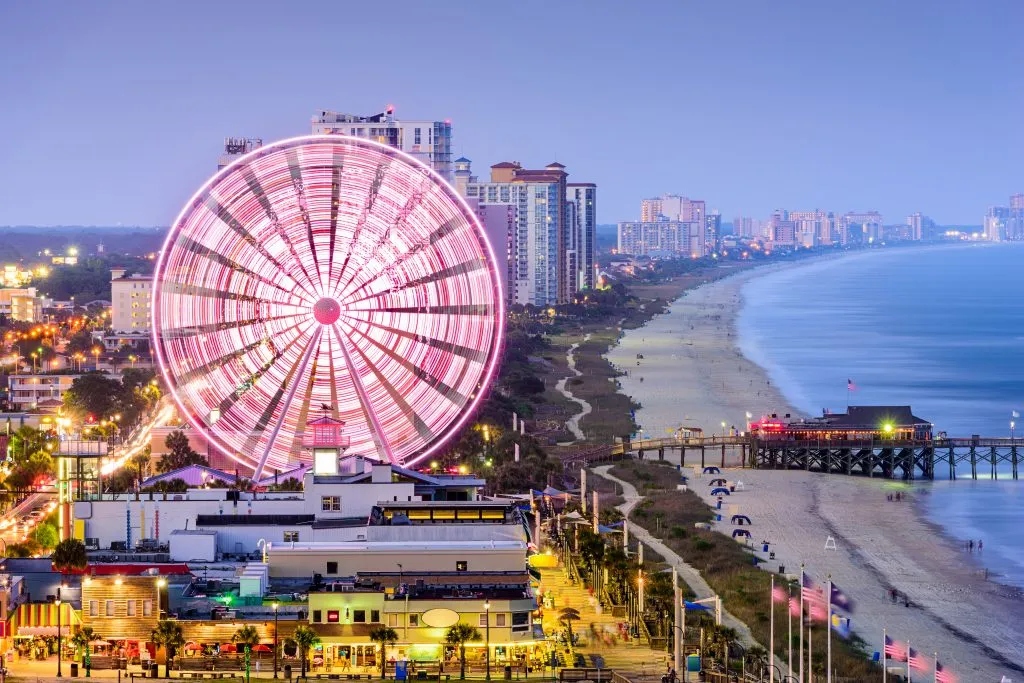 lit up ferris wheel spinning near the beach at night myrtle beach, one of the best weekend getaways south coast