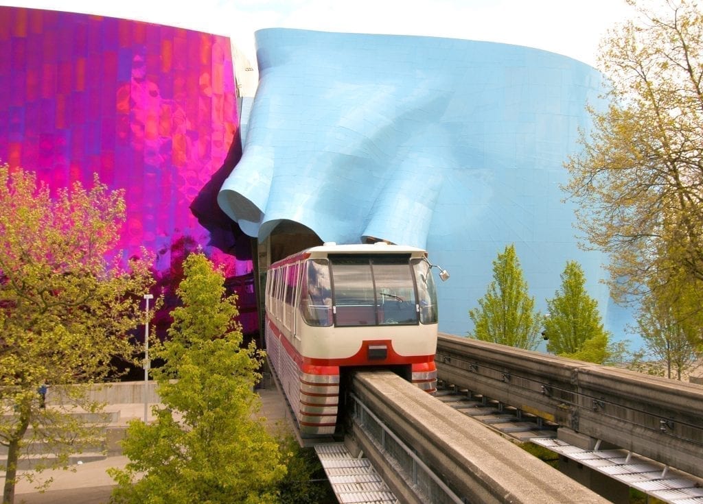 Seattle Monorail leaving a colorful tunnel, with purple on one side of the tunnel and blue on the other