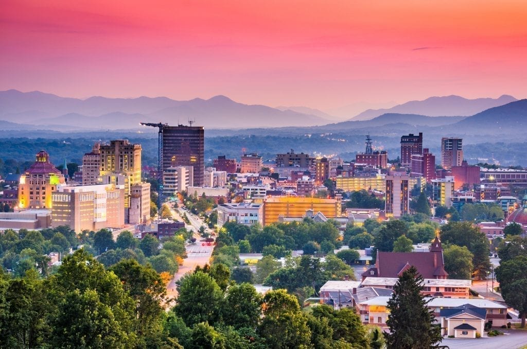 Skyline of Asheville NC at sunset with Blue Ridge Mountains in the background, one of the best weekend trips in the south