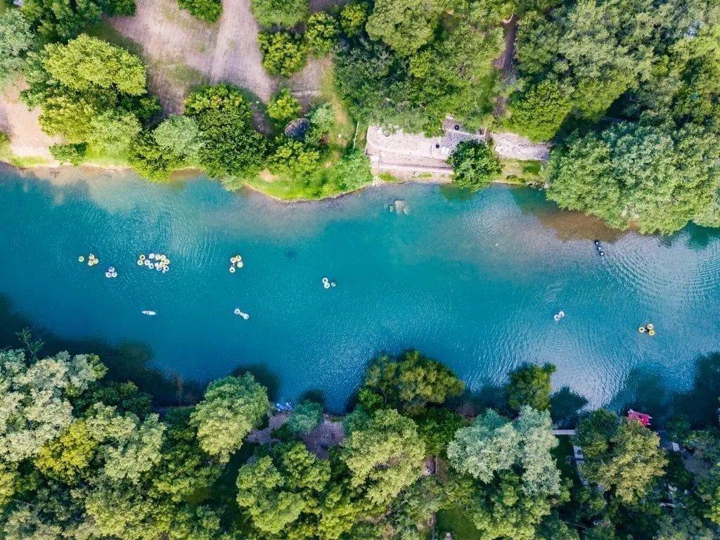 Drone photo from above of a Texas river with people floating in intertubes down it