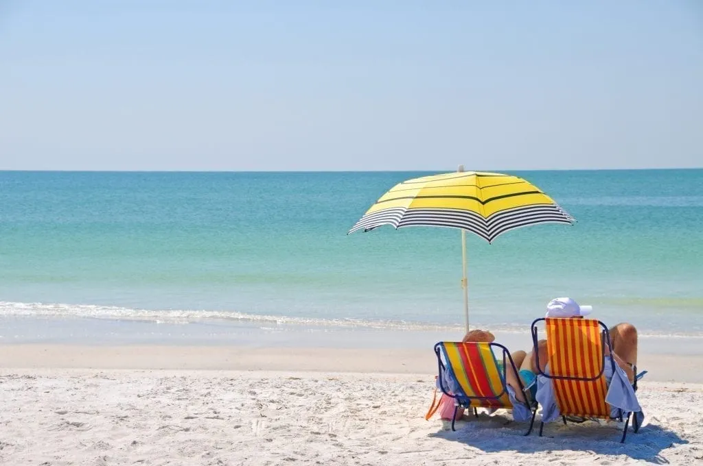 Couple sitting on the beach under a yellow umbrella in Destin Florida, one of the best places to visit in the south