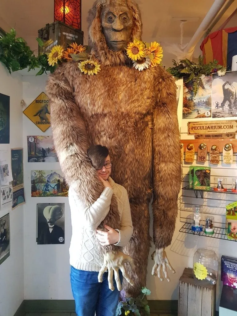 The author of this Portland blog post holding onto a sasquatch statue at the portland peculiarium