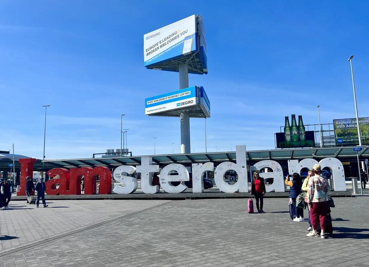 iamsterdam sign at schipol airport on a sunny day with a few people standing in front of it