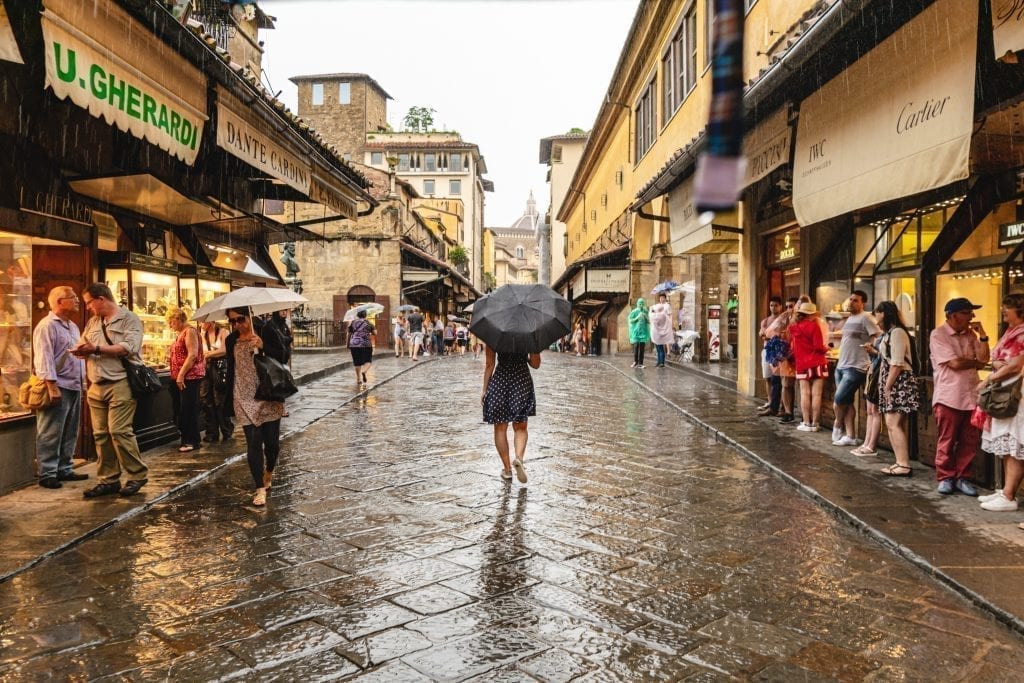 kate storm walking across the ponte vecchio in the rain in florence italy