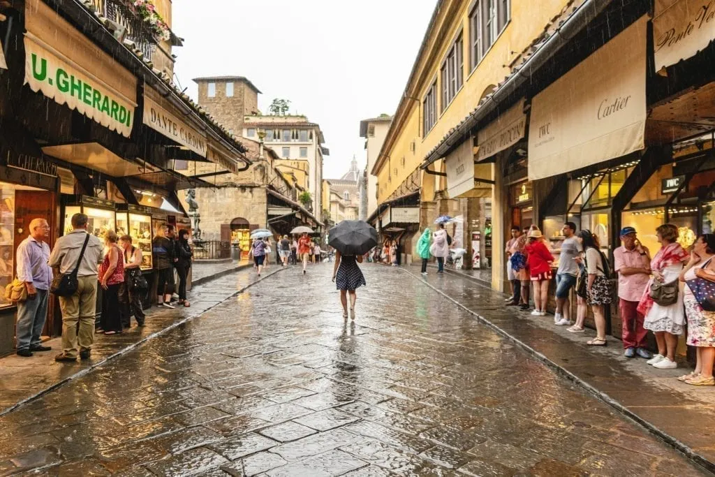 kate storm walking across the ponte vecchio in florence tuscany in may rainy day